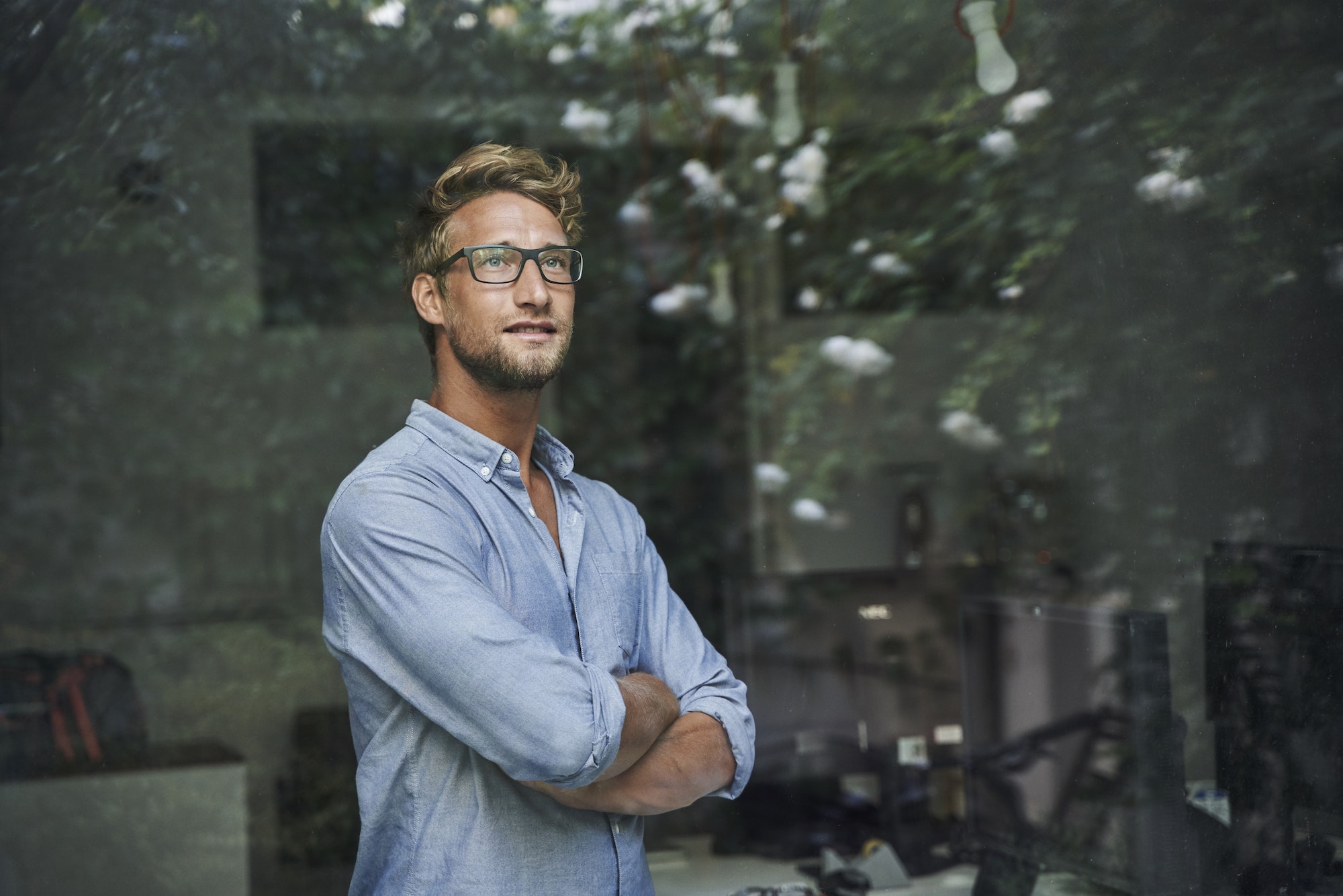 Casual young businessman behind windowpane in office