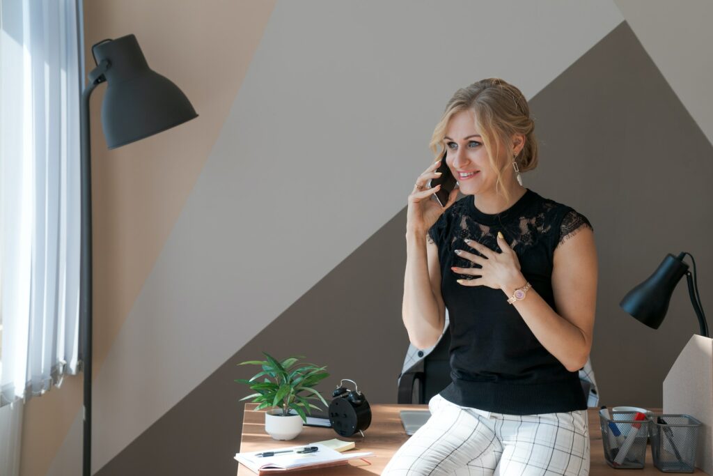 Smiling business woman using phone in office. Small business entrepreneur looks