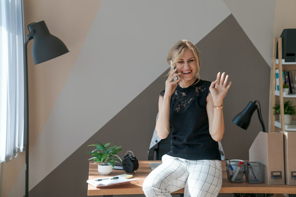 Smiling business woman using phone in office. Small business entrepreneur looks